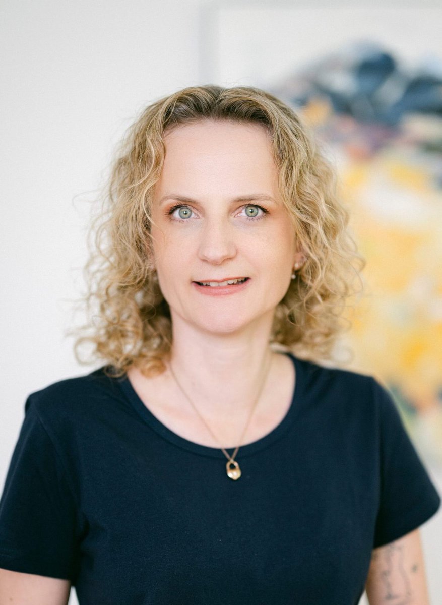 Porträt von Frau Brunnhuber. Sie trägt eine goldene Kette und hat gelocktes, blondes Haar.