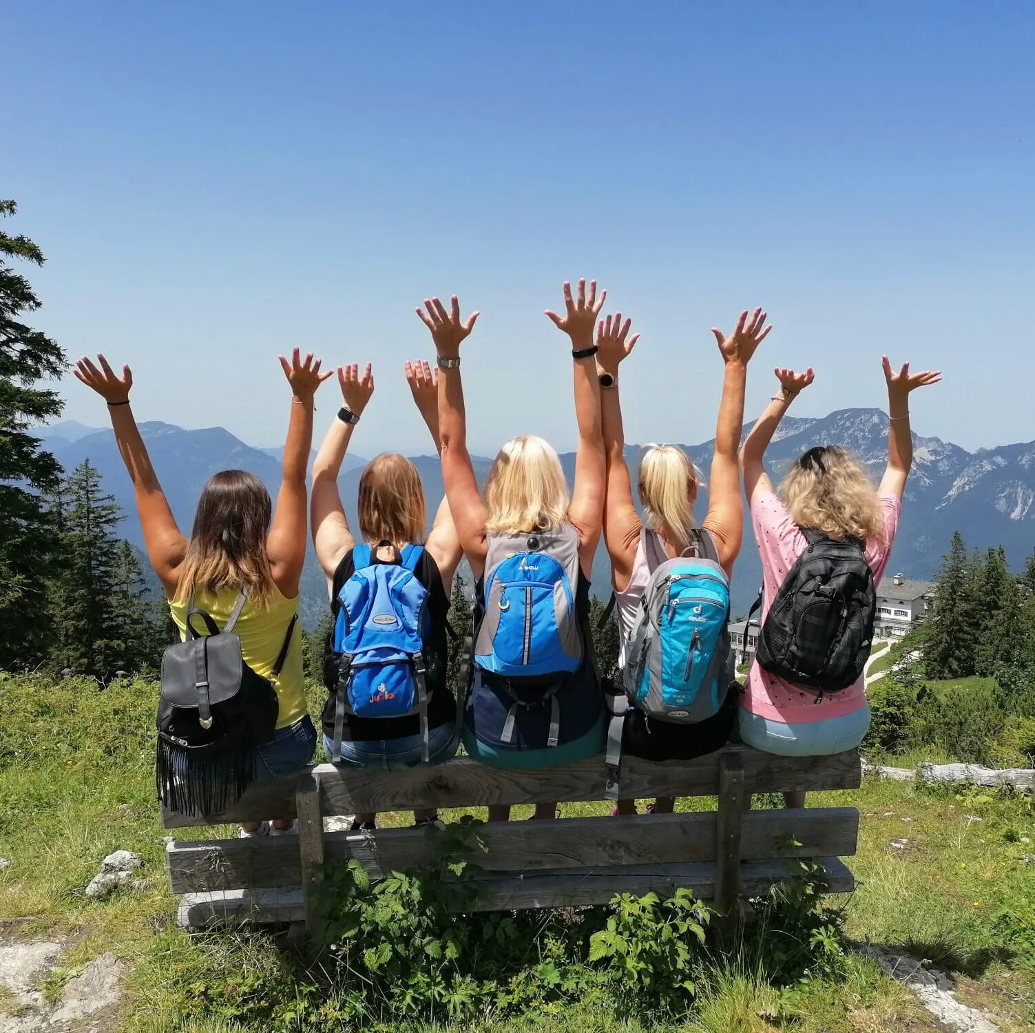 Das Praxenteam sitzt auf einer Bank und reißt die Hände in die Luft. Sie sitzen vor einem schönen Bergpanorama und sind eindeutig auf einem gemeinsamen Wandertrip unterwegs.